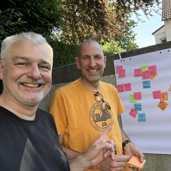 Jens Thiemann und ein Kollege draußen vor einem Flipchart mit Haftnotizen